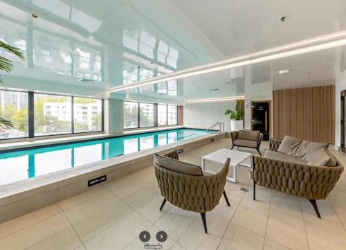 a swimming pool in a building with chairs and a couch at Sky Stars CBD Apartment in Auckland