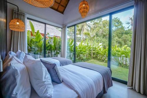 1 Schlafzimmer mit 2 Betten und einem großen Fenster in der Unterkunft 4BR Luxury Tropical Jungle Villa 4 Mins to Beach in Tanah Lot