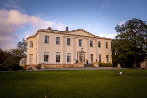 a large white house with a large grass field at Owston Hall Hotel in Doncaster