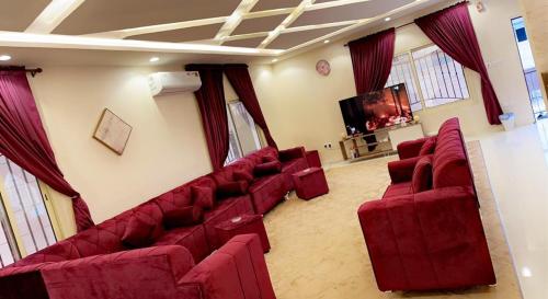 a living room with red couches and a flat screen tv at Flowers of Al hada in Al Hada