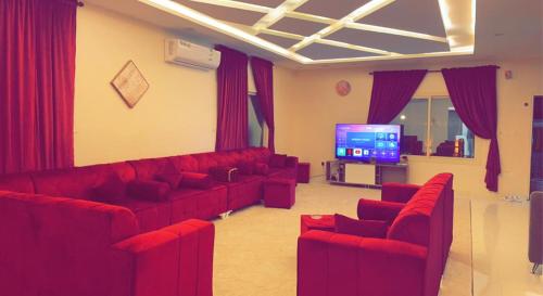 a living room with red couches and a flat screen tv at Flowers of Al hada in Al Hada