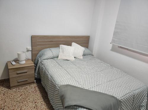 a bedroom with a bed and a wooden headboard and a night stand at Alojamiento El palmeral in Santa Pola