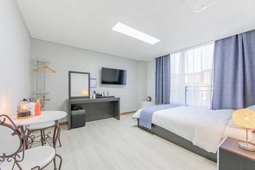 ヨス市にあるJin Arirang Hostelのベッド、テーブル、椅子が備わるホテルルームです。