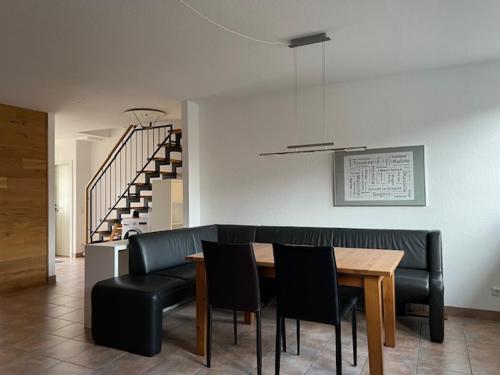 a dining room with a table and black leather chairs at Ferienwohnung Kirchhellen "Lepper Eck" in Bottrop-Kirchhellen