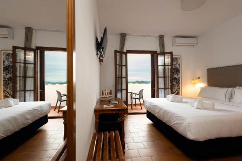 a hotel room with two beds and a balcony at Hotel Tugasa Villa de Algar in Algar