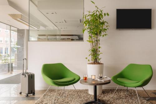 two green chairs and a table with a potted plant at Crown Hotel Eindhoven Centre in Eindhoven