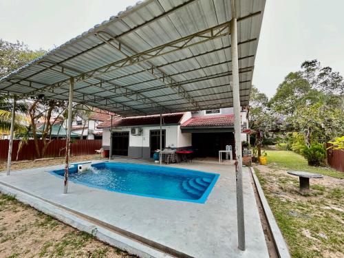 toldo sobre uma piscina num quintal em A Famosa resort villa 877 snooker karaoke BBQ 5BR em Kampong Alor Gajah