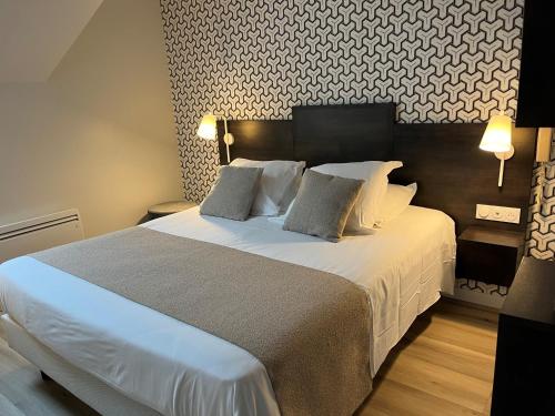 a bedroom with a large white bed with two pillows at Logis - Hôtel de la Baie de Somme in Le Crotoy