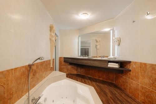 a bathroom with a tub and a large mirror at Leonardo Hotel Eindhoven City Center in Eindhoven
