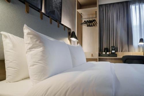 a bedroom with a white bed with white pillows at Campanile Prime Paris 19 - La Villette in Paris
