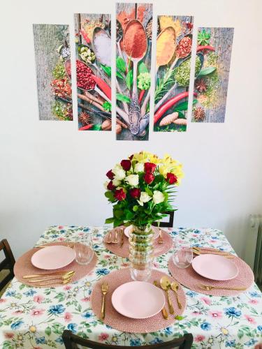 a table with plates and a vase of flowers on it at Joseph Hayn Apartments in Sighişoara