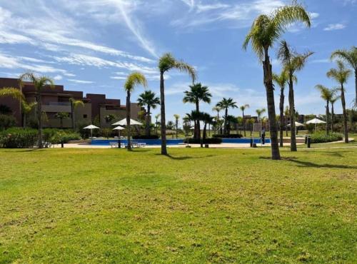 a park with palm trees in front of a building at Appartement 3 chambres en rez-de-jardin avec piscine Prestigia Marrakech in Marrakesh