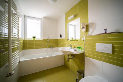 ein Badezimmer mit Badewanne, Waschbecken und Badewanne Tubermottermott in der Unterkunft Garni hotel Svitavy in Svitavy