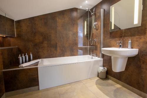 a bathroom with a bath tub and a sink at Dunston Stables- Spectacular Countryside Setting in Newton Abbot