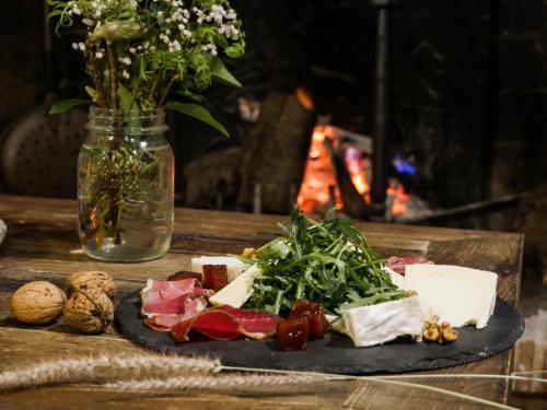 a plate of cheese and vegetables on a table with a vase of flowers at Demeures et Châteaux Moulin des Templiers Hôtel & SPA in Pontaubert