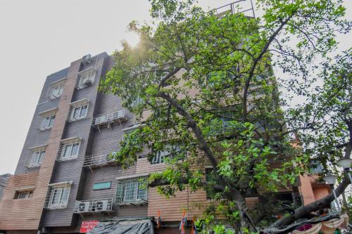 ein hohes Gebäude mit einem Baum davor in der Unterkunft Super OYO Krishna Guest House in Kalkutta