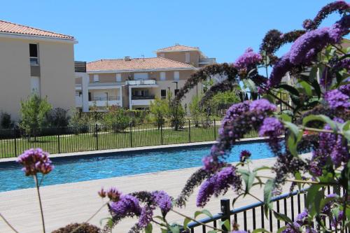 - une vue sur la piscine ornée de fleurs violettes dans l'établissement Très bel appartement pour 3 avec piscine à Chateau Vert, à La Londe-les-Maures