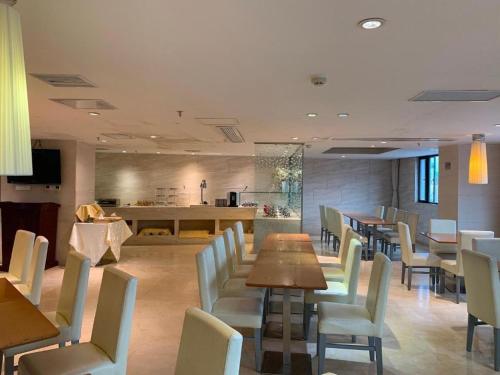 a restaurant with tables and chairs and a kitchen at JI Hotel Shenzhen Convention Center in Shenzhen