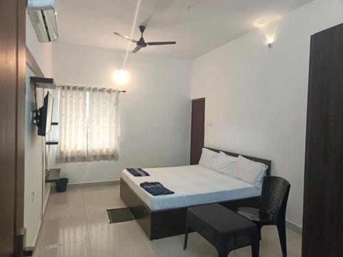 een kleine slaapkamer met een bed en een stoel bij ARIVU LODGE AC in Coimbatore