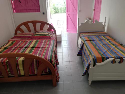 two beds in a room with pink doors at Au Paradis Créole in Dubédou