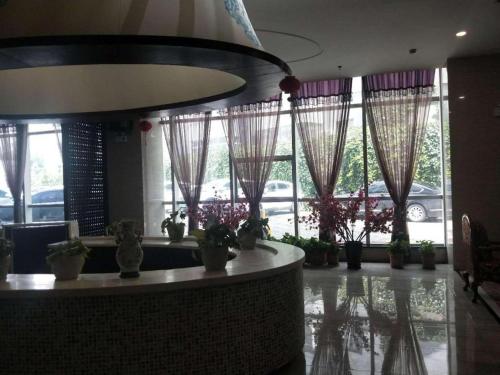 a lobby with potted plants and windows in a building at Xana Hotelle Yining Airport Road Jinwuyuan in Kipekyüzi
