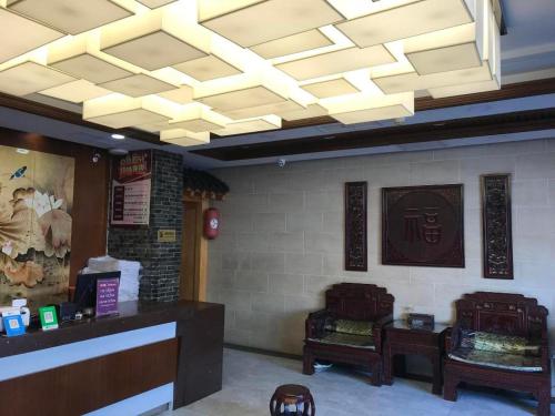 uma sala de jantar com tecto em caixote e um restaurante em PAI Hotels Jinzhou Yi County Railway Station em Yi