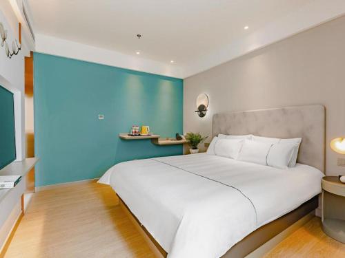 a bedroom with a large white bed with a blue wall at Magnotel Tai'an Luohe Park Luohe Street in Tai'an