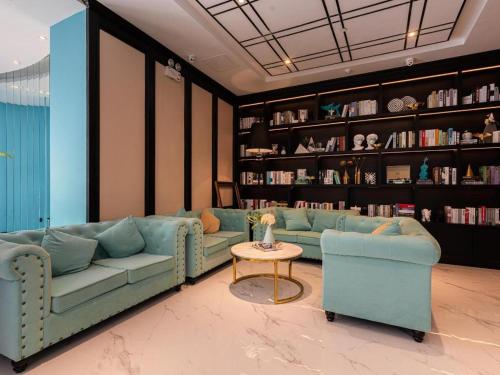 a living room with blue couches and a book shelf at Xana Hotelle Chaozhou Ancient City Paifang Street in Chaozhou
