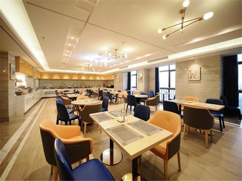 a restaurant with tables and chairs and a kitchen at Kyriad Hotel Changsha Environmental Protection Science and Technology Park in Yangtianhu