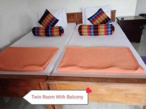 two twin beds in a room with avertisementforgrimgrim at The Rock Face in Ella