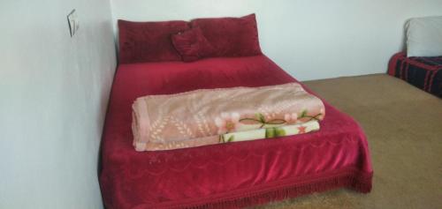 ein rotes Bett mit einer roten Bettdecke darauf in der Unterkunft Familles avec bébé in Fès