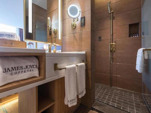 een badkamer met een douche en een wastafel met handdoeken bij James Joyce Coffetel Tangshan Zunhua Film City in Zunhua