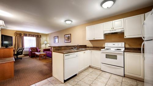 a kitchen with white appliances and a living room at Best Western Plus Osoyoos Hotel & Suites in Osoyoos