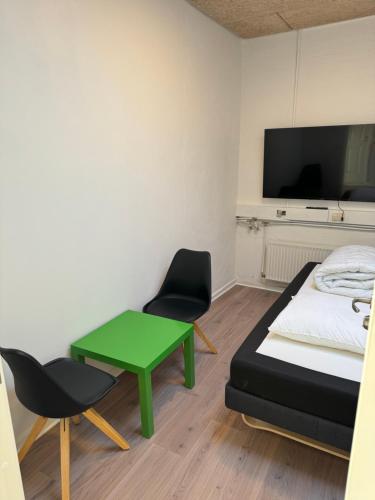 Habitación con cama, mesa verde y sillas. en Italian Rooms 7 en Aalborg