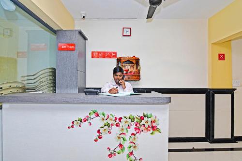 a woman sitting at a counter talking on a cell phone at Hotel O Ashwarya Service Apartment in Navi Mumbai