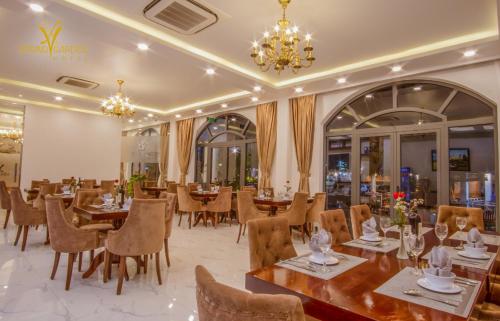 ein Restaurant mit Tischen, Stühlen und einem Kronleuchter in der Unterkunft SPRING GARDEN HOTEL LK in Long Khanh