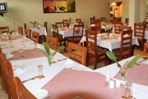 un comedor con mesas blancas y sillas de madera en Roban Hotels Ltd, en Enugu