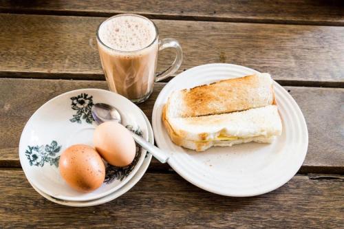 un sándwich y huevos en un plato junto a una taza de café en MEGARA HOTEL PEKANBARU en Pekanbaru