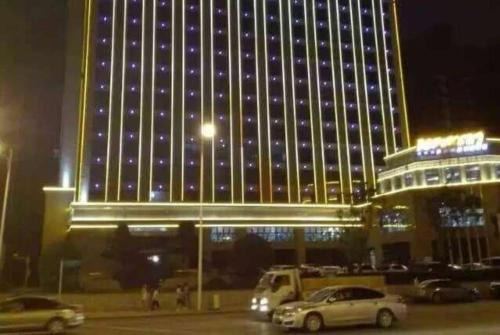 un gran edificio con coches estacionados frente a él en Days Hotel by Wyndham Hunan Changsha Convoy en Muyun