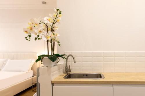 FARNESINA SUITE في روما: مطبخ مع حوض مع إناء من الزهور