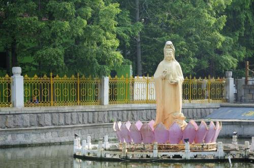 Eine Statue einer Frau mit rosa Stühlen im Wasser. in der Unterkunft City 118 Hotel Qingdao Boardcast Tower in Qingdao