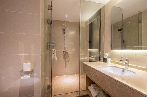 a bathroom with a sink and a glass shower at City Comfort Inn Loudi High-speed Railway South Station Municipal Government in Loudi
