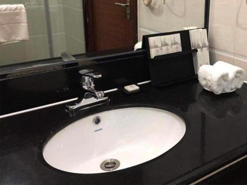 ein Waschbecken im Bad mit einer schwarzen Arbeitsplatte in der Unterkunft Borrman Hotel Meizhou Mei County Airport in Meizhou