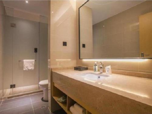 a bathroom with a sink and a mirror and a toilet at City Comfort Inn Wuhan Tianhe Airport Outlets in Huanghualao