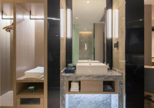 W łazience znajduje się umywalka i lustro. w obiekcie Echarm Hotel Wuhan Tianhe Airport Outlets w mieście Huanghualao
