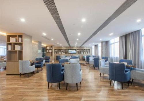 a waiting room with blue chairs and tables in a building at Echarm Hotel Wuhan Tianhe Airport Outlets in Huanghualao