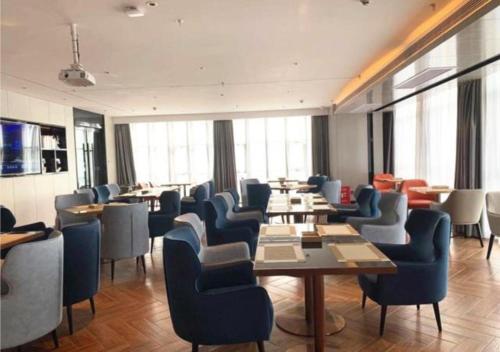 un restaurant avec des chaises bleues, des tables et des fenêtres dans l'établissement Echarm Hotel Jingzhou Olympic Sports Center, à Pu-ho