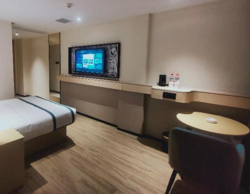 a hotel room with a bed and a flat screen tv at City Comfort Inn Changsha South Railyway Station West Square in Yangtianhu