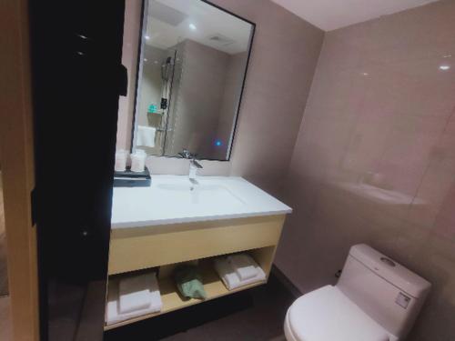 a bathroom with a sink and a toilet and a mirror at City Comfort Inn Changsha South Railyway Station West Square in Yangtianhu