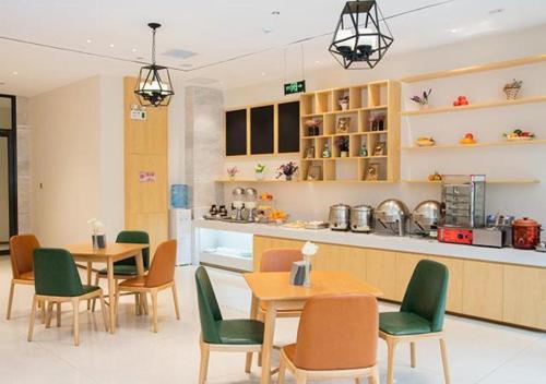 昆明市にあるCity Comfort Inn Kunming Xinluojiu Bay Guangju Roadのテーブルと椅子、カウンター付きのレストラン